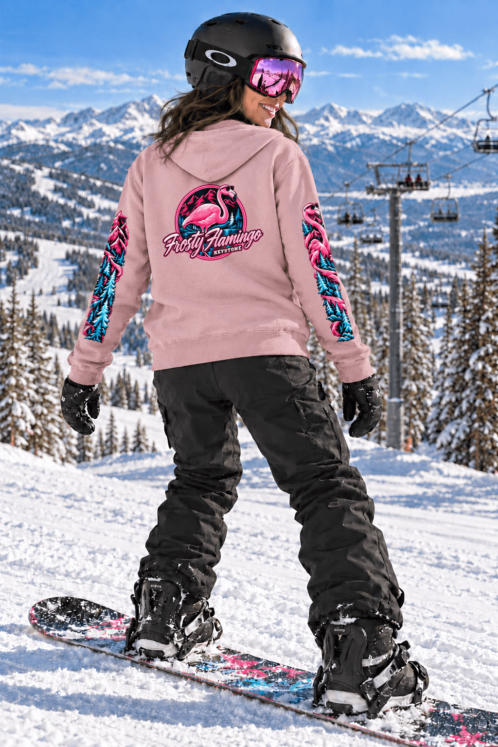 Brunette snowboarder wearing the Blush Frosty Flamingo Keystone hoodie on a snowy mountain